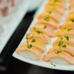 Assorted sushi arranged on a ceramic platter with chopsticks
